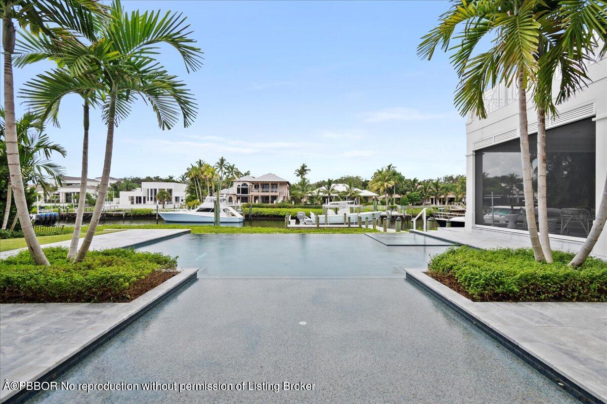159 Commodore Drive Jupiter, FL 33477 - Photo 9 of 20 a view of a swimming pool with a lawn chair and palm trees