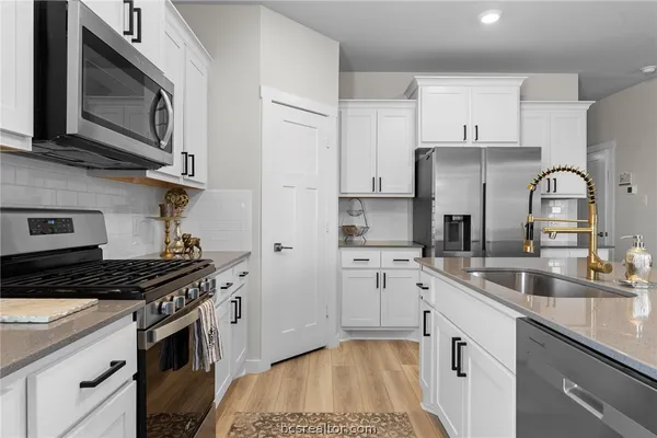 a kitchen with stainless steel appliances a sink stove and cabinets