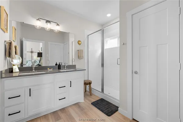a spacious bathroom with a double vanity sink a mirror and a shower