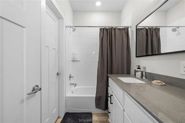 a bathroom with a granite countertop sink a mirror a shower and a bathtub
