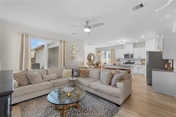 a living room with furniture and a dining table with wooden floor