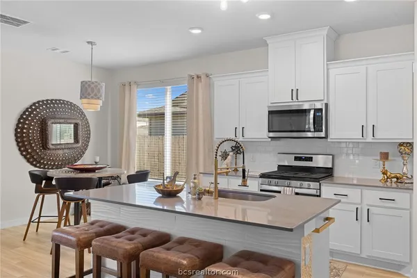 a kitchen with kitchen island granite countertop a stove a sink a dining table and chairs
