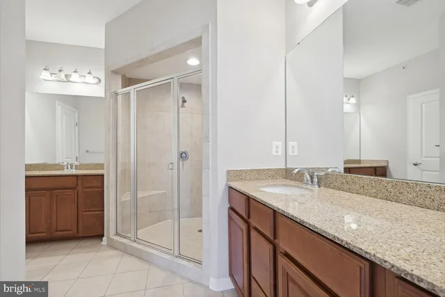 a bathroom with a granite countertop sink a mirror and a shower