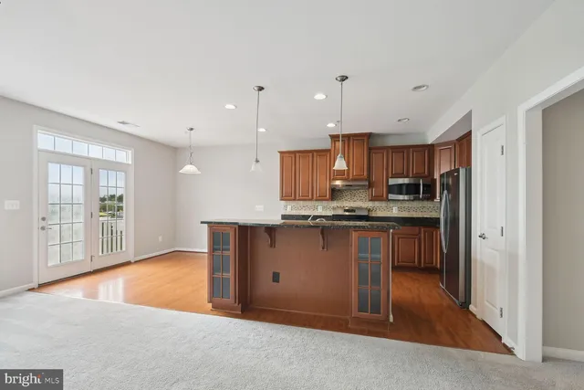 a kitchen with stainless steel appliances granite countertop a refrigerator a sink a stove and a oven with wooden floor