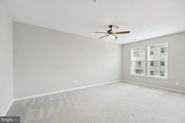 an empty room with chandelier fan and windows