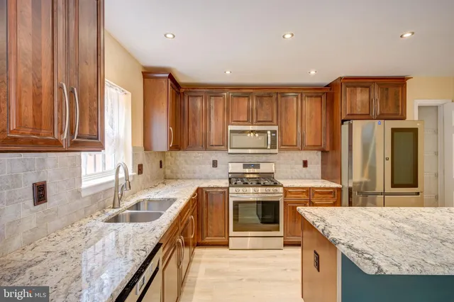 a kitchen with stainless steel appliances granite countertop a sink stove microwave and refrigerator