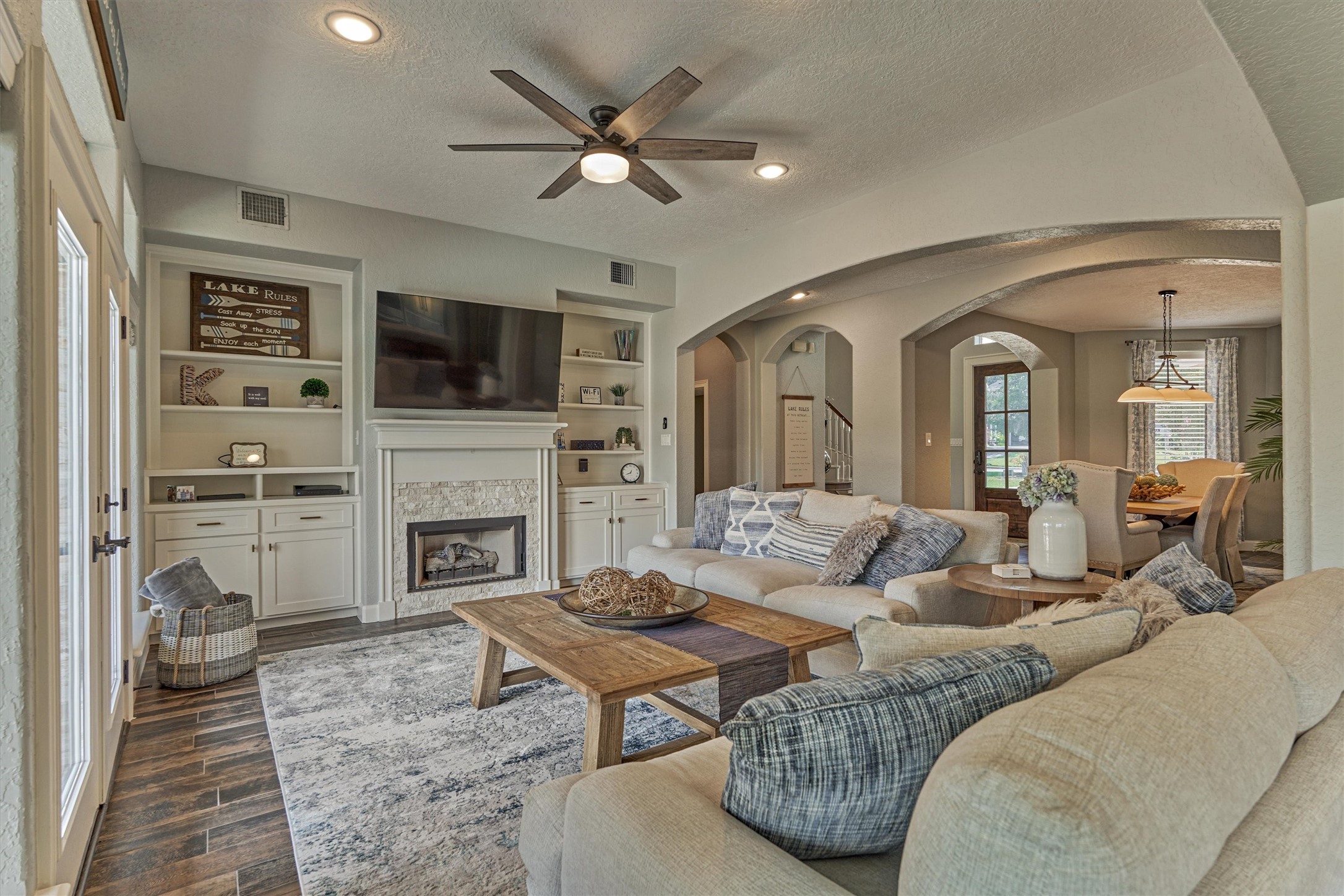 202 Edgemar Road Montgomery, TX 77356 - Photo 14 of 50 Inviting living room with fireplace and built-ins, flowing through graceful arches to the dining area—styled in timeless, neutral tones.