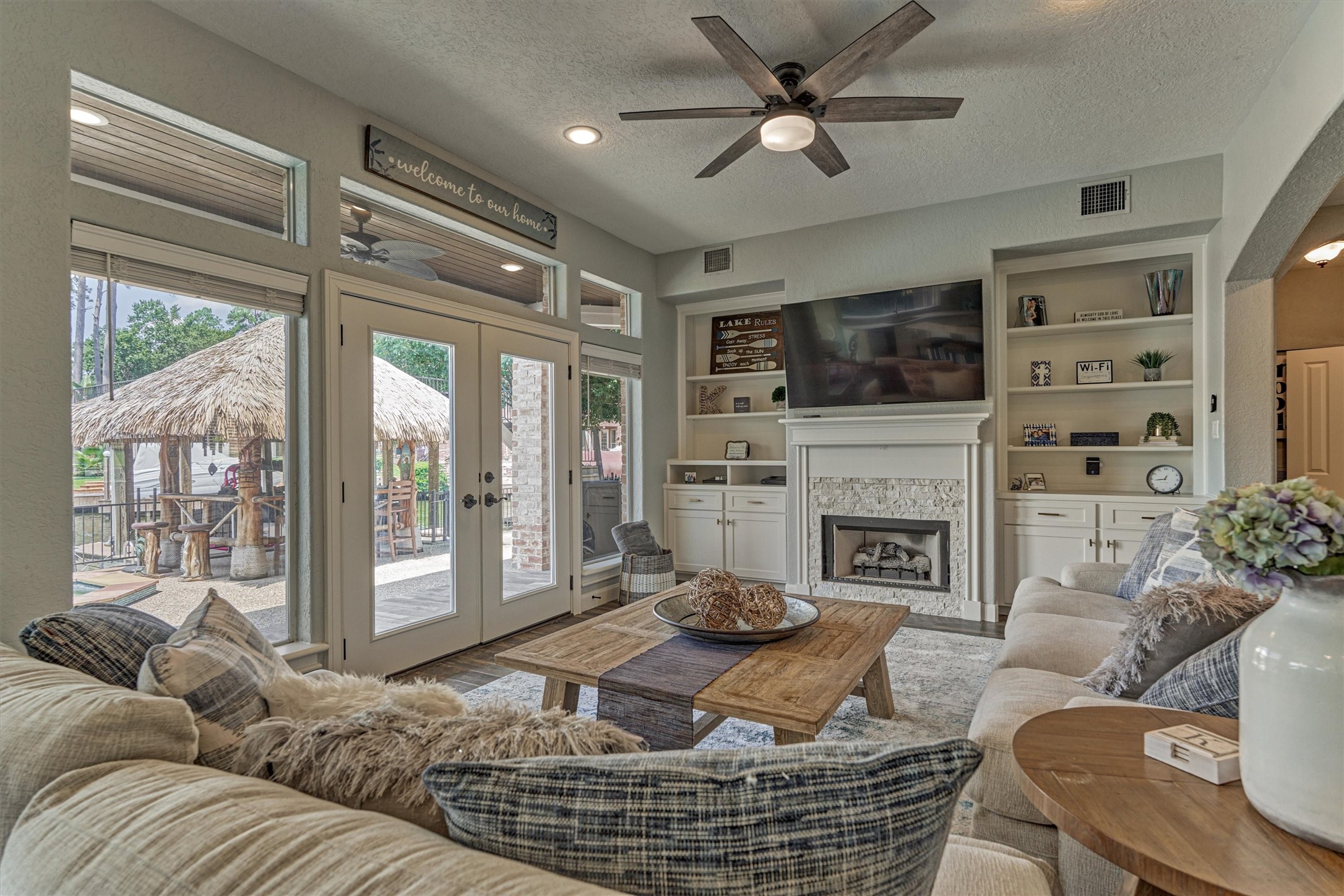 202 Edgemar Road Montgomery, TX 77356 - Photo 16 of 50 This cozy living room features a modern ceiling fan, built-in shelving, and a fireplace with a mounted TV.