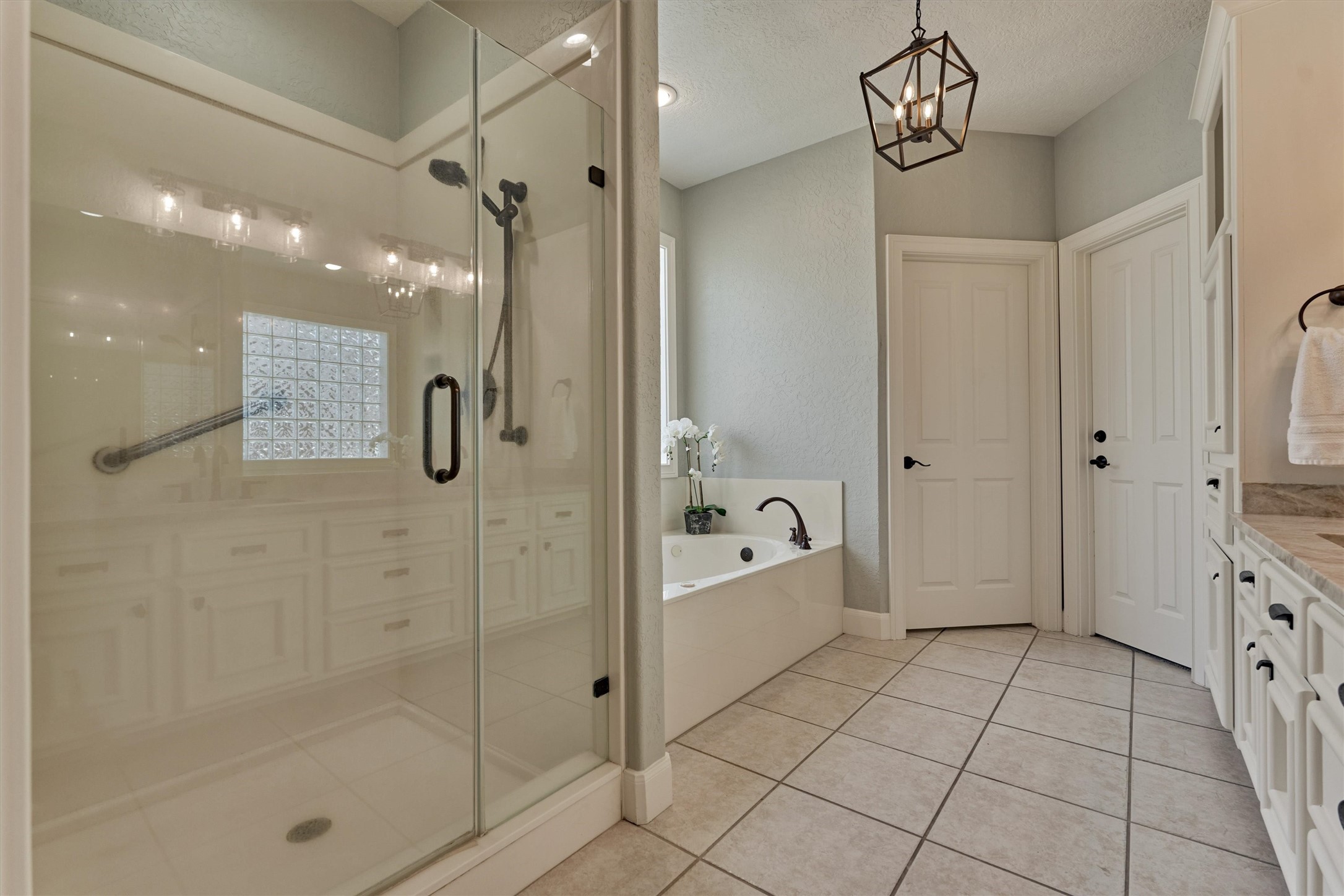 202 Edgemar Road Montgomery, TX 77356 - Photo 28 of 50 A spa-inspired retreat with a glass-enclosed shower with stoop, modern soaking tub, and elegant cabinetry. Neutral tile and sleek lighting create a sophisticated ambiance.