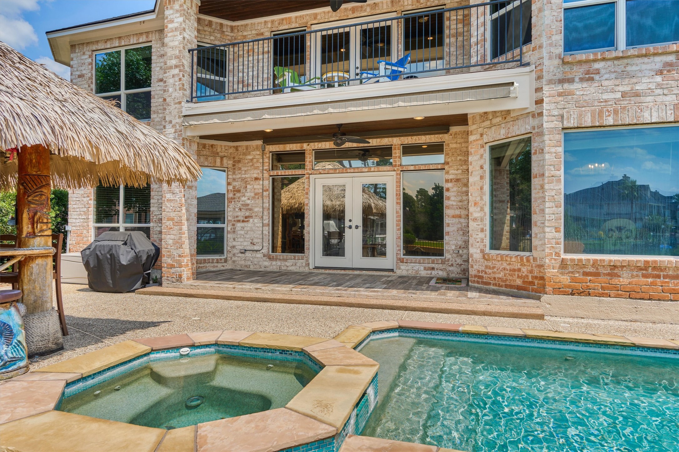202 Edgemar Road Montgomery, TX 77356 - Photo 39 of 50 Resort-style living with a sparkling saltwater pool and spa, second-story balcony, and Margaritaville-inspired tiki bar. The covered porch extends with an automated Sunbrella shade, offering effortless comfort and protection on sunny Texas days.