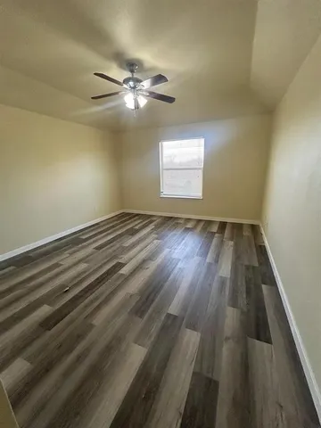 en empty room with wooden floor fan and window