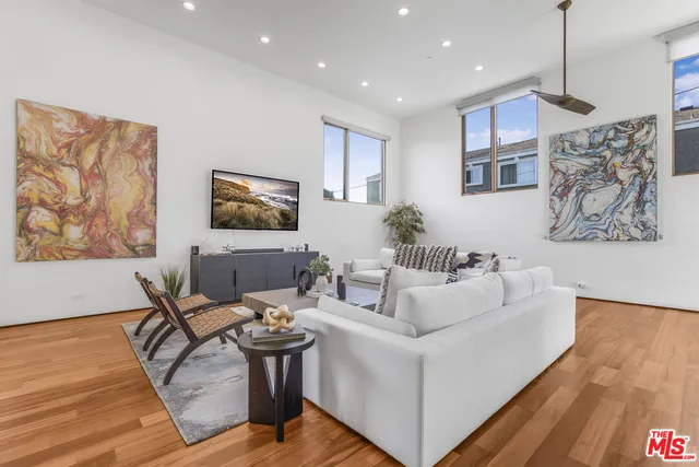 a living room with furniture a wooden floor and painting on the wall