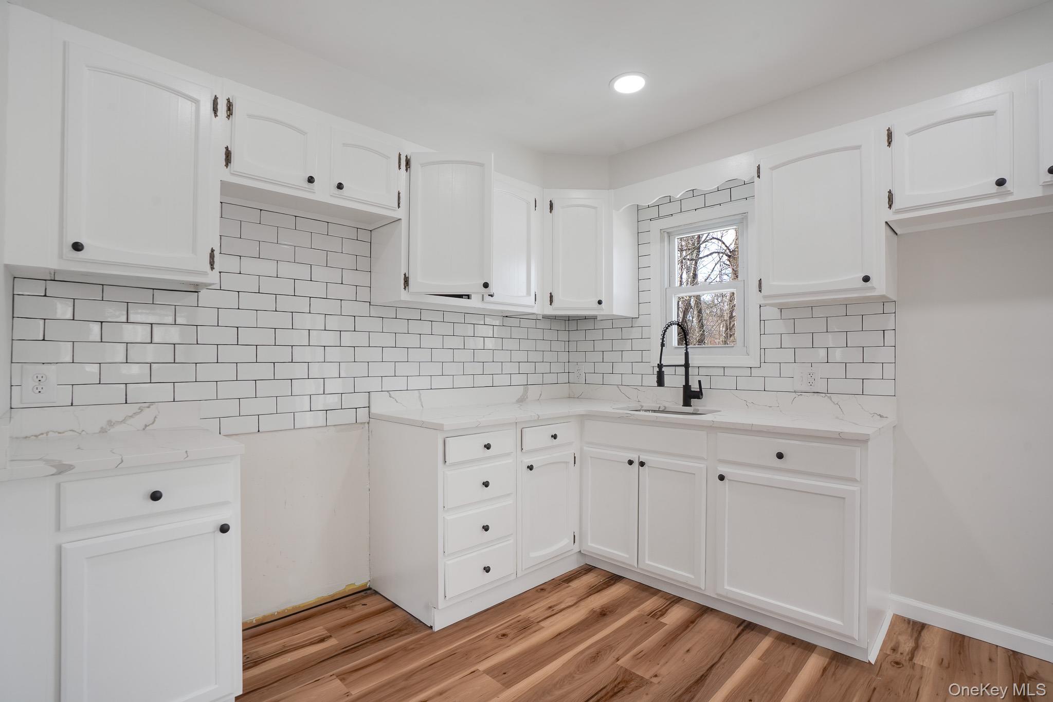 629 Twin Arch Road Rock Tavern, NY 12575 - Photo 7 of 24 a kitchen with white cabinets a sink a stove and wooden floor