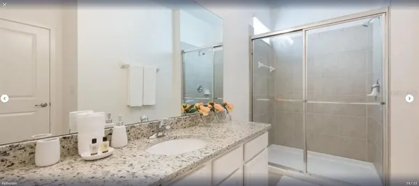 a bathroom with a granite countertop sink a mirror and shower