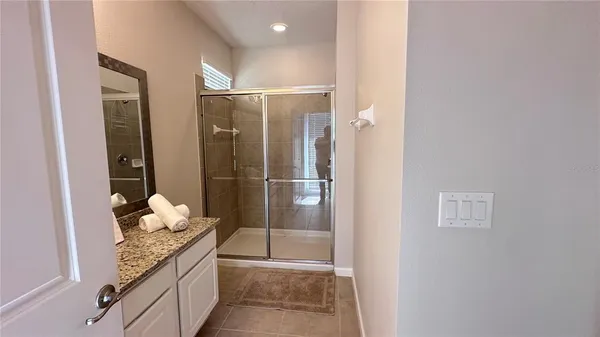 a bathroom with a granite countertop sink a mirror and shower