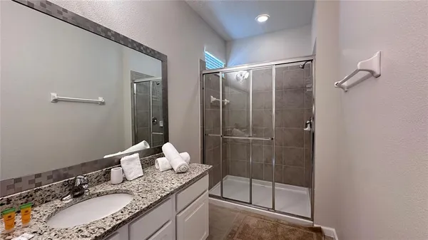 a bathroom with a granite countertop sink a mirror and shower