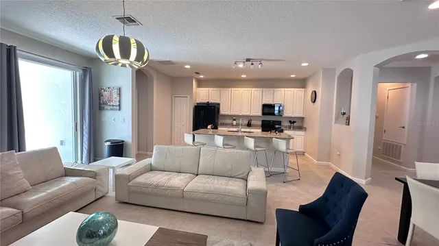 a living room with furniture kitchen and a chandelier