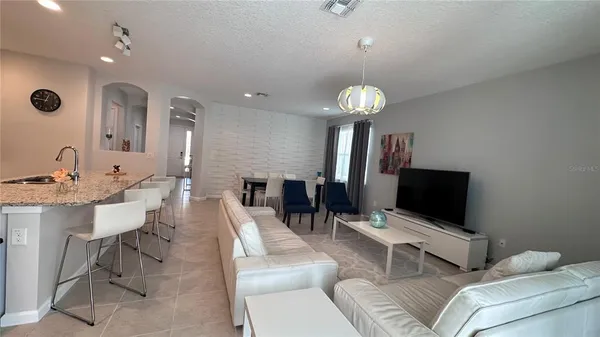 a living room with furniture a chandelier and a flat screen tv
