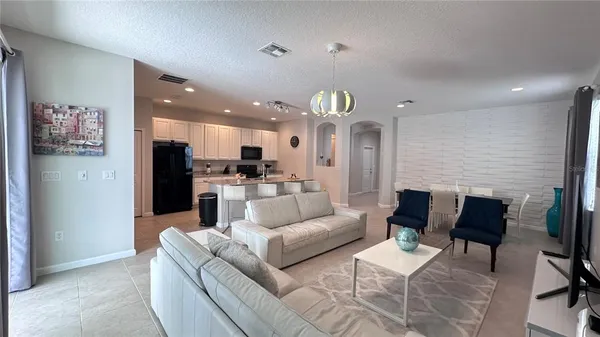 a living room with furniture kitchen view and a chandelier