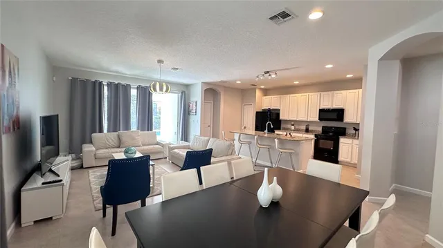 a living room with furniture kitchen view and a chandelier
