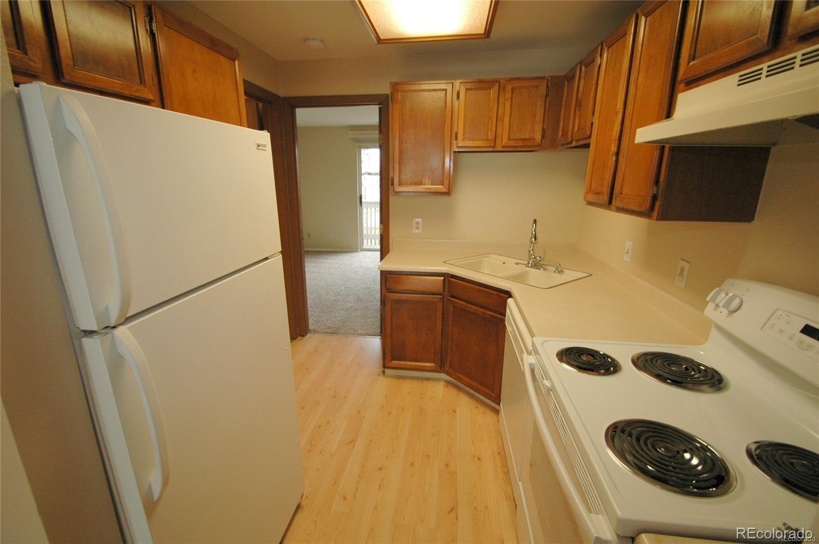 165 South Sable Boulevard, Unit R23 Aurora, CO 80012 - Photo 4 of 11 a kitchen with a refrigerator and a stove