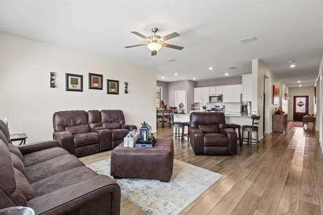 a living room with furniture kitchen view and a wooden floor