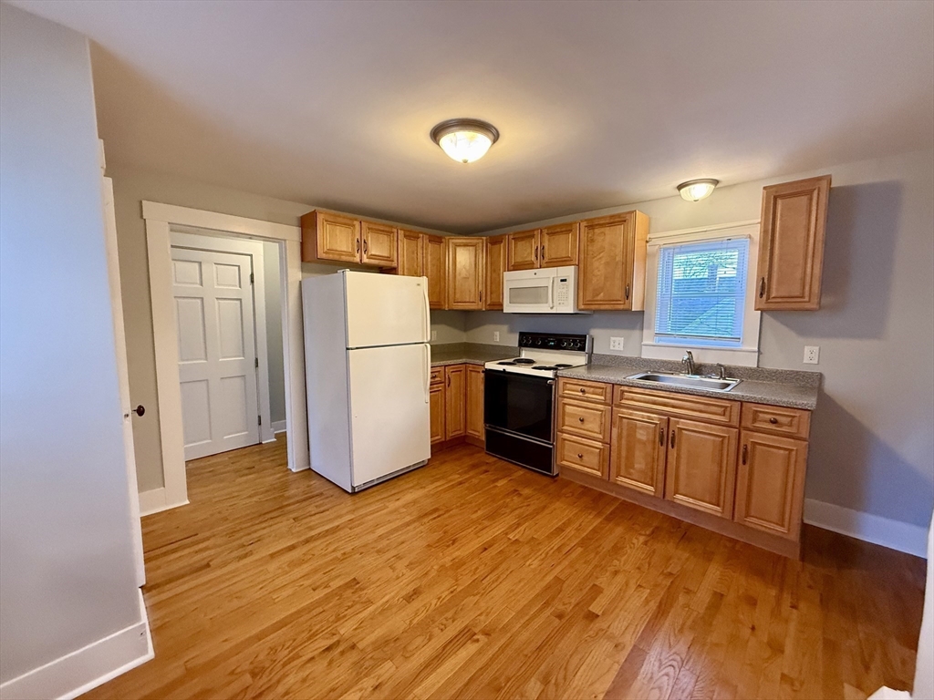 19 Ruggles Street, Unit 2 Westborough, MA 01581 - Photo 4 of 14 a kitchen with granite countertop a refrigerator stove top oven and sink