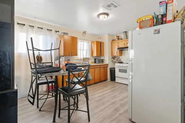 a kitchen with stainless steel appliances a stove a refrigerator and a dining table with wooden floor