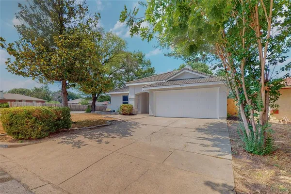 a front view of a house with a garden and trees