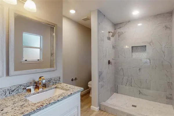 a bathroom with a granite countertop sink a mirror and shower