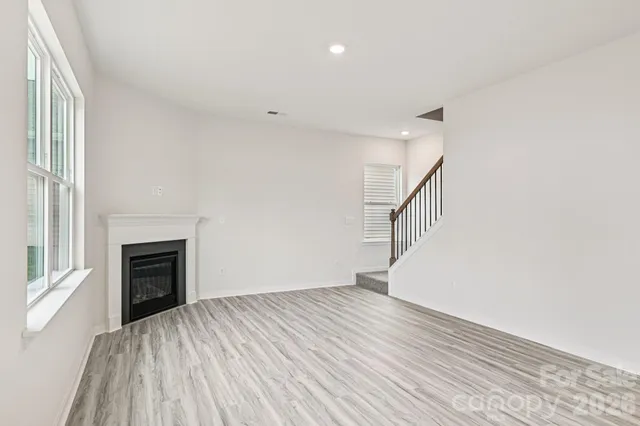 a view of empty room with wooden floor and fireplace