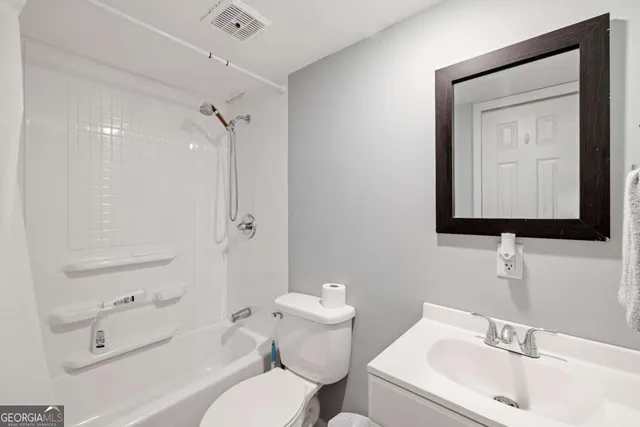 a bathroom with a toilet sink vanity and mirror