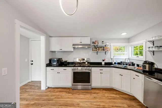 a kitchen with stainless steel appliances granite countertop a stove a sink and a microwave