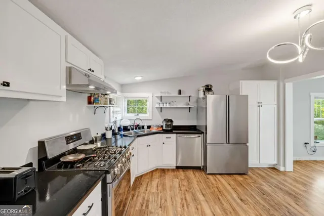 a kitchen with granite countertop a refrigerator stove and sink