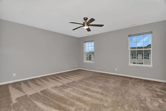 a view of empty room with window and ceiling fan