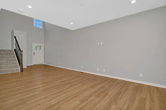 a view of an empty room with wooden floor and stairs