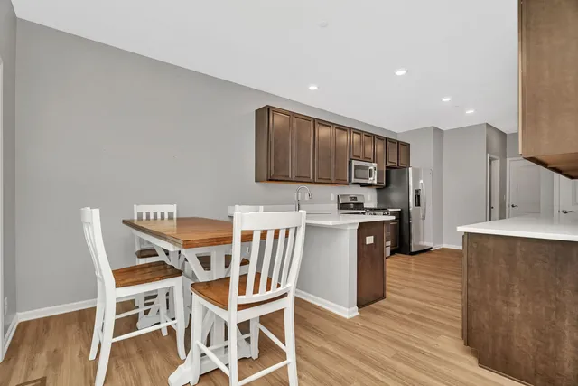 a kitchen with stainless steel appliances kitchen island granite countertop a table chairs stove microwave and cabinets