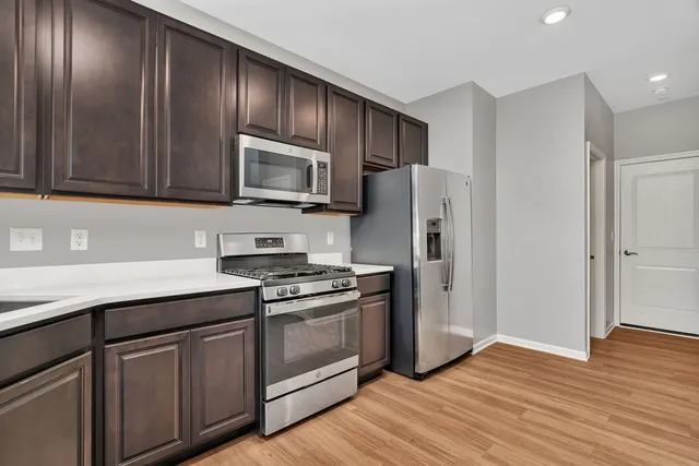 a kitchen with granite countertop wooden cabinets stainless steel appliances and a wooden floor