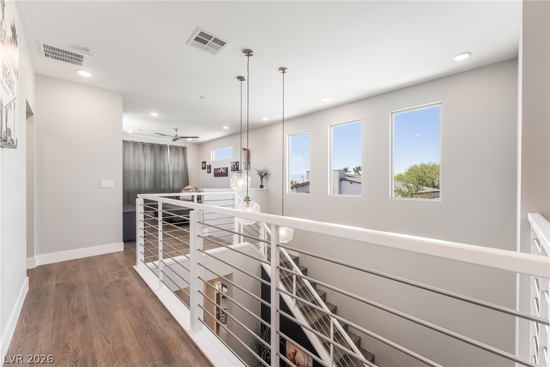 2166 Trivero Street Henderson, NV 89044 - Photo 18 of 61 Natural light floods this hallway, featuring contemporary cable railings and warm wooden flooring.