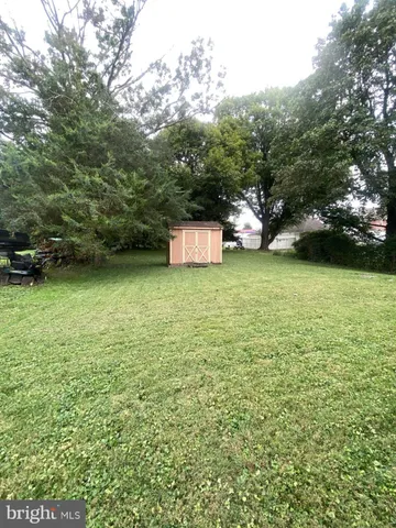 a view of a green yard with a house and large trees