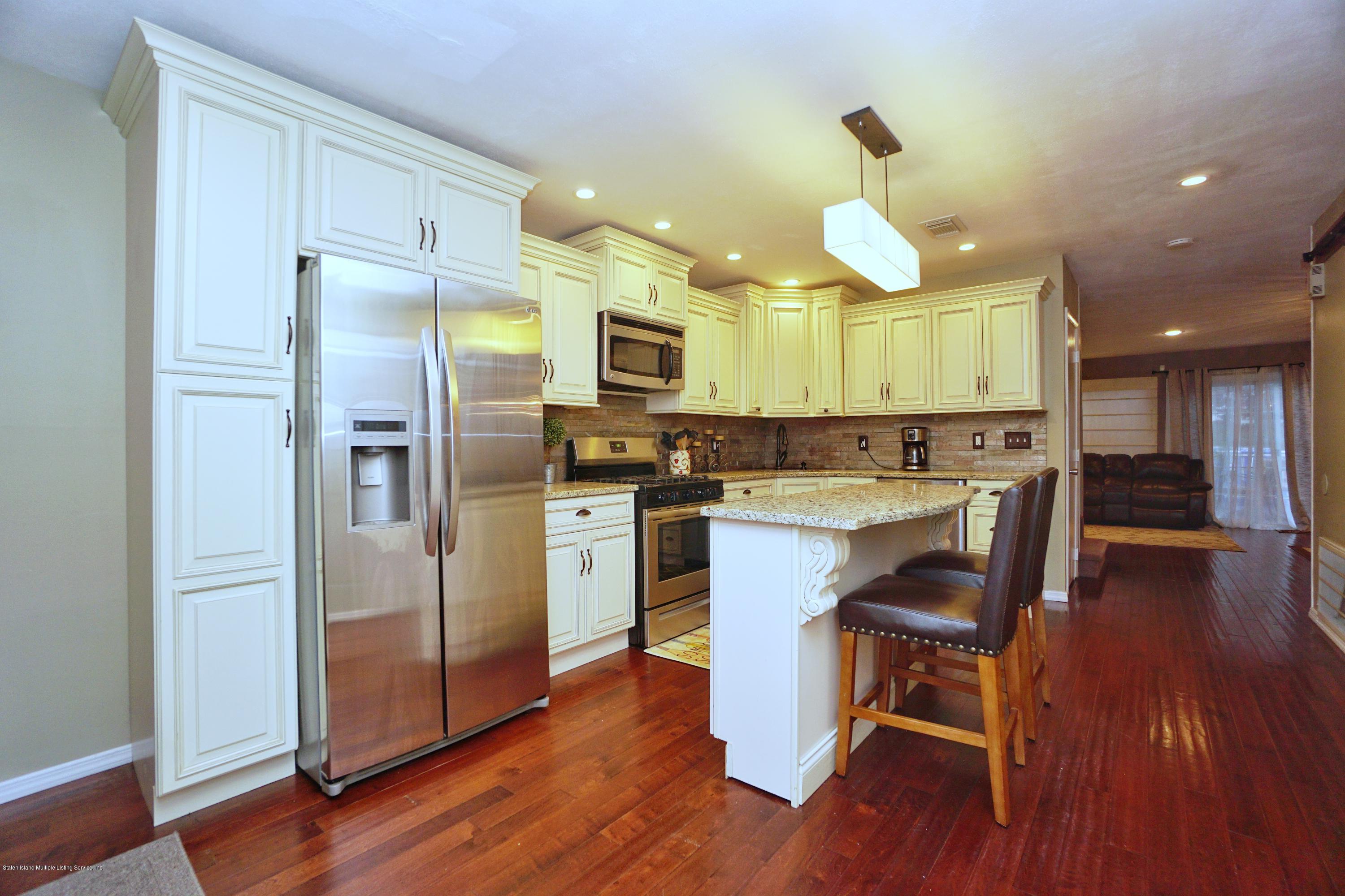 43 Forest Green Staten Island, NY 10312 - Photo 2 of 30 a kitchen with stainless steel appliances granite countertop a refrigerator a sink dishwasher a stove and white cabinets with wooden floor