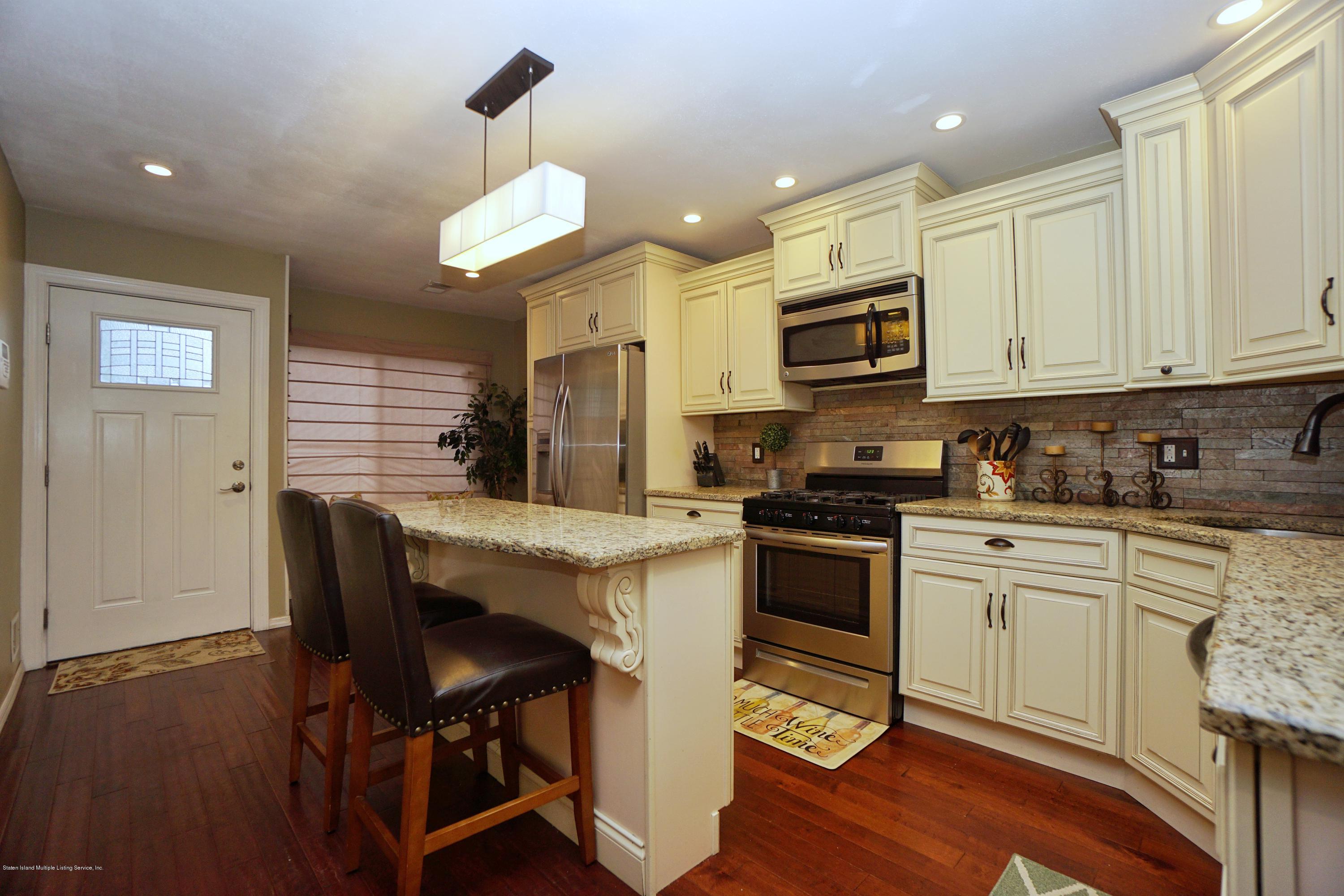 43 Forest Green Staten Island, NY 10312 - Photo 6 of 30 a kitchen with stainless steel appliances granite countertop a stove top oven a sink dishwasher a dining table and chairs with wooden floor