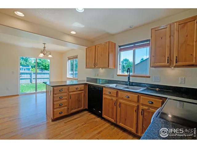 a kitchen with granite countertop wooden cabinets a stove a sink and a large window
