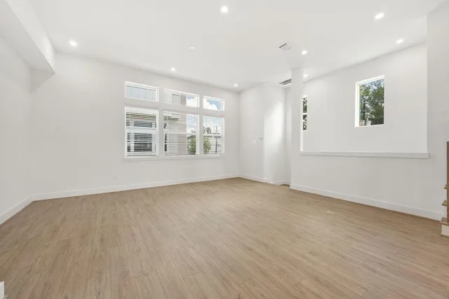 an empty room with wooden floor and windows