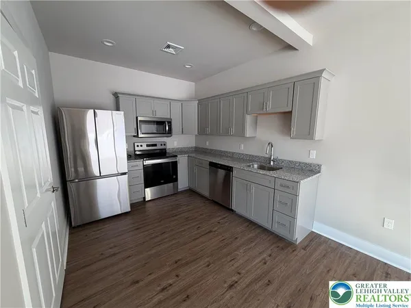 a kitchen with stainless steel appliances a refrigerator a stove top oven a sink and cabinets