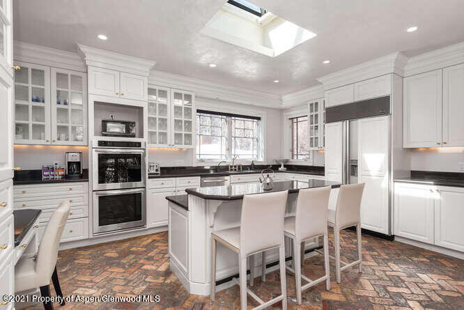 825 Ute Avenue, Unit A Aspen, CO 81611 - Photo 10 of 23 a kitchen with stainless steel appliances kitchen island granite countertop a stove top oven a refrigerator a sink and a dining table with white cabinets