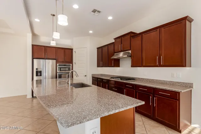 a large kitchen with kitchen island a large counter top stainless steel appliances and cabinets