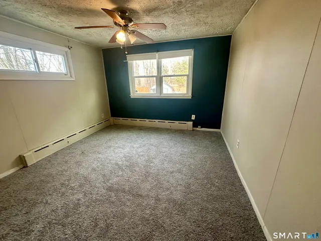 an empty room with windows and fan