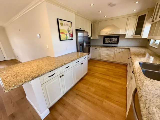 a large kitchen with stainless steel appliances kitchen island granite countertop a sink and cabinets