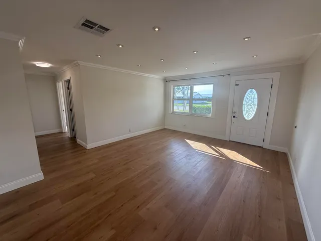 a view of empty room with wooden floor and window